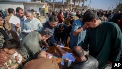 FILE - Supporters of Shiite cleric Muqtada al-Sadr sign a pledge to stand against LGBTQ rights, outside a mosque in Kufa, Iraq, Dec. 2, 2022.