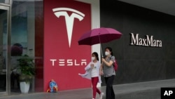 资料照：行人走过北京的一家特斯拉专卖店。（2023年5月31日）