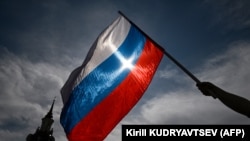 Seorang pria mengibarkan bendera nasional Rusia di pusat kota Moskow menjelang Hari Rusia pada 11 Juni 2023. (Foto: AFP/Kirill KUDRYAVTSEV)