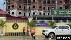 แฟ้ม - พนง.ส่งของยืนหน้าสถานกักตัวผู้อพยพที่สีหนุวิลล์ 26 ก.ย. 2022 (Photo by AFP)