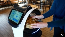 Seorang pelanggan menerima makanan yang diantarkan oleh robot BellaBot di restoran Noodle Topia di Madison Heights, Michigan, 20 Maret 2023. (AP/Carlos Osorio)