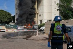 Automobili u plamenu na parkingu ispred stambene zgrade nakon udara raketa iz Pojasa Gaze, u Aškelonu, južni Izrael, 7. oktobra 2023.