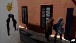 FILE - Migrants walk inside the medieval core at the old city of the divided capital Nicosia, Cyprus, May 10, 2023. 