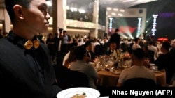 A waiter serves food at the Michelin Guide ceremony in Hanoi on June 6, 2023. Vietnam's booming food scene was awarded its first-ever Michelin stars Tuesday, with four restaurants selected by the prestigious dining guide. (Photo by Nhac Nguyen/AFP)