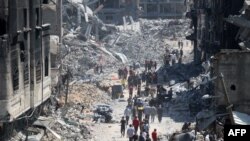 Warga Palestina membawa beberapa barang yang diselamatkan ketika mereka meninggalkan kamp pengungsi Jabalia di Jalur Gaza utara setelah mereka kembali sebentar untuk memeriksa rumah mereka pada tanggal 31 Mei 2024. (Omar AL-QATTAA / AFP)