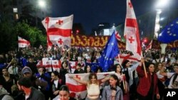 FILE - Demonstrators with Georgian national and EU flags rally during an opposition protest against a foreign influence bill as they mark their country's Independence Day, in the center of in Tbilisi, Georgia, May 26, 2024.