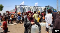 Seorang perempuan tampak membawa jeriken setelah mengisinya dengan air dari truk bantuan yang tiba di Rafah, di selatan Jalur Gaza, pada 25 Juni 2024. (Foto: AFP/Eyad Baba)
