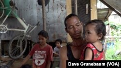 In Taguig, Philippines, May 18, 2023, parent Joeson Dalanon holds his one-year-old son Nick Maron. Dalanon told VOA “I hear there are lots of kids who die” from vaccines.