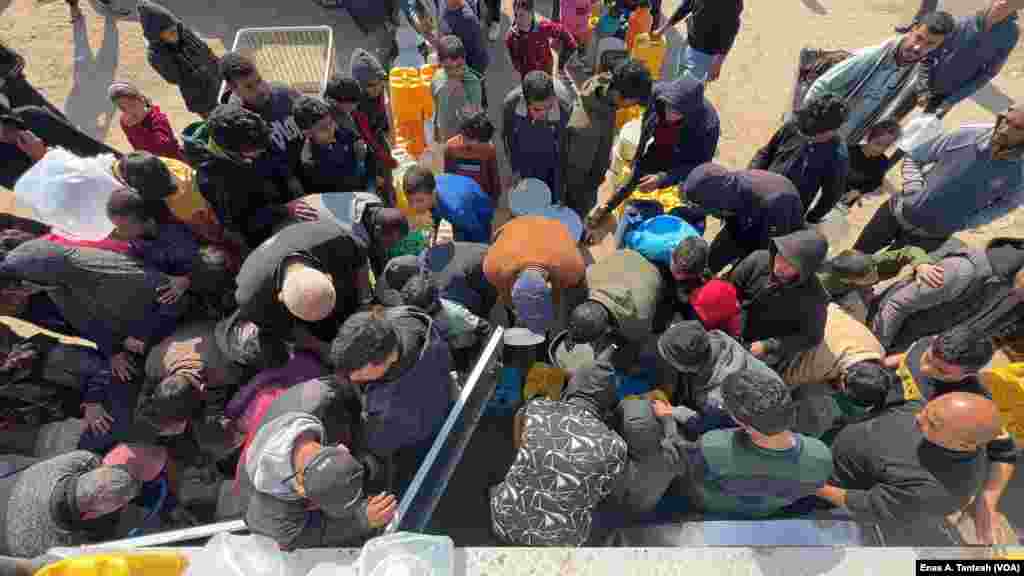 Families queue to collect water for drinking and bathing in Rafah, Gaza, in Feb. 2024.