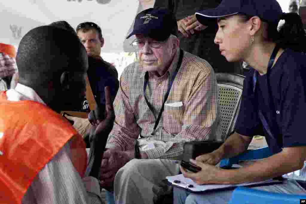 Поранешниот американски претседател Џими Картер разговара со претставник на гласачкото место на избирачко место надвор од Џуба, јужен Судан, 13 април 2010 година. Организацијата на Картер, Центарот Картер, распореди тим набљудувачи за изборите. Распространетите проблеми со гласањето ги натераа суданските власти да го продолжат периодот на гласање од три на пет дена.