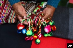 An Aymara Indigenous woman shows handwoven woolen crafts made on the sidelines of a fashion show showcasing Indigenous creations at Zofri Mall in Iquique, Chile, Saturday, July 29, 2023. (AP Photo/Ignacio Munoz)
