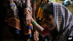 FILE - A woman holds the hand of her relative as family members of people trapped under rubble wail after a landslide washed away houses in Raigad district, western Maharashtra state, India, July 20, 2023.