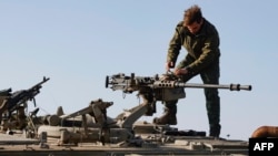 Seorang tentara Israel memeriksa senjata di sebuah posisi di Dataran Tinggi Golan yang dianeksasi Israel dekat perbatasan dengan Suriah, 28 Desember 2023. (Foto: AFP)