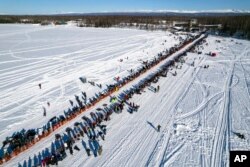 FILE - A competitor mushes across Willow Lake during the Iditarod Trail Sled Dog Race, in Willow, Alaska, March 6, 2022.