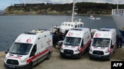 Ambulans diparkir di dekat perahu penjaga pantai saat petugas menurunkan jenazah dua puluh satu migran yang tenggelam setelah perahu yang membawa mereka terbalik di lepas pantai Turki di Laut Aegea, 15 Maret 2024. (Demiroren News AAgency / DHA (Demiroren News Agency) / AFP) 
