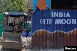 A roadside vendor waits for customers as he sits next to a mural ahead of G20 Summit, in New Delhi, Sept. 5, 2023.