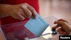 A voter casts a ballot in the second round of the early French parliamentary elections, at a polling station in Vanves near Paris, July 7, 2024.