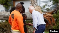 U.S. President Joe Biden shakes hands with a child, next to first lady Jill Biden, during their tour of Hurricane Idalia storm destruction, Live Oak, Florida, Sept. 2, 2023.