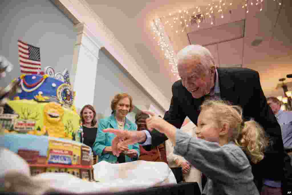 Поранешната прва дама Розалин Картер (лево) гледа како поранешниот претседател Џими Картер и внукот Ерол (4) гледаат во роденденска торта за време на прославата на неговиот 90-ти роденден одржана на Универзитетот Џорџија Југозападен, на 4 октомври 2014 година, во САД, Џорџија.