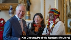 Raja Inggris Charles III menerima cendera mata dari pemimpin adat Amazon, Domingo Peas, dalam resepsi di Istana Buckingham, London, Jumat, 17 Februari 2023. (Foto: Kin Cheung/Pool via Reuters)