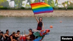 A woman holds a Rainbow flag after competing in a dragon boat during the annual Dragon Boat Festival in Taipei, Taiwan, June 22, 2023. 