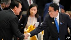 윤석열 한국 대통령과 기시다 후미오 일본 총리가 지난해 11월 캄보디아 프놈펜에서 열린 아세안-동아시아 정상회의장에서 악수하고 있다.
