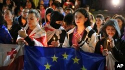 Demonstrators with Georgian and EU flags and candles stand in front of the Kashveti Church of St. George during an opposition protest against a draft "foreign agents" bill in the center of Tbilisi, Georgia, May 3, 2024.