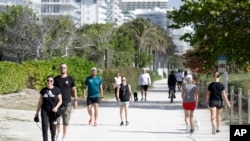 ILUSTRASI - Orang-orang berjalan-jalan dengan anjing mereka dan berolahraga di jalan yang padat di sepanjang sisi pantai, Sabtu, 21 Maret 2020, di Surfside, Florida. (AP/Wilfredo Lee)