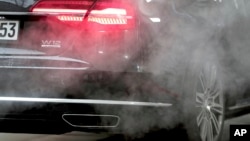 In this file photo, a luxury Audi car is surrounded by exhaust gases as it is parked with a running engine in front of the Chancellery in Berlin, Germany, Wednesday, Nov. 20, 2019. (AP Photo/Michael Sohn, File)