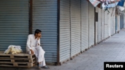 A man sits beside closed shops during a strike against recent price increases, in Karachi, Pakistan, Feb. 27, 2023.