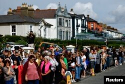 People gather outside late Irish singer Sinead O'Connor's former home on the day of her funeral procession, in Bray, Ireland, Aug. 8, 2023.