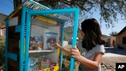 เอลิซา คาซาเรซ วัย 9 ขวบ เติมของในตู้เย็นสาธารณะ ช่วงการระบาดของโควิด-19 5 เมษายน 2020 (ภาพ: เอพี)