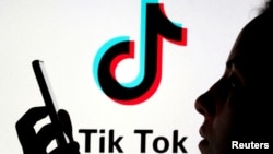 FILE - A person holds a smartphone as Tik Tok logo is displayed behind in this picture illustration taken Nov. 7, 2019. 