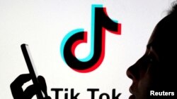 FILE - A person holds a smartphone as Tik Tok logo is displayed behind in this picture illustration taken Nov. 7, 2019. 
