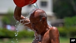 A man pours water on himself during a hot summer day at a park in Karachi, Pakistan, May 21, 2024. 