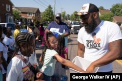 Quientest Vinson, right, of Turn Up Knox hands out candy to children during the Lonsdale Neighborhood Homecoming celebration Saturday, Aug. 5, 2023 in Knoxville, Tenn. The organization is a centerpiece of Knoxville's attempt to follow a science-based playbook to fight a surge in fatal and non-fatal shootings. (AP Photo/George Walker IV)