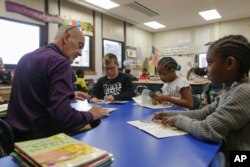 Richard Evans, a teacher at Hyde Park Elementary School, helps Shaundrea Baines, right, during a reading circle in class on Thursday, Oct. 20, 2022, in Niagara Falls, N.Y. (AP Photo/Joshua Bessex)