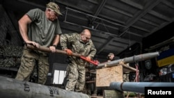 Members of the company tactical group "Steppe Wolves" of the Voluntary Formation of the Zaporizhzhia Territorial Community disassemble a shell for a BM-21 Grad multiple launch rocket system in Zaporizhzhia region, Ukraine, April 26, 2024.
