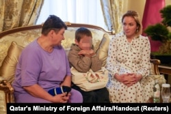 A 7-year-old Ukrainian boy sits by his grandmother, left, and Russia's Commissioner for Children's Rights, Maria Lvova-Belova, after being released to Qatari diplomats, at Qatar's embassy in Moscow, Russia, Oct. 13, 2023. (Qatar's Ministry of Foreign Affairs/Handout via Reuters)