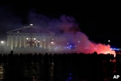 Demonstrators gather next to a burning barricade as they stage next to the National Assembly during a protest in Paris, Friday, March 17, 2023.
