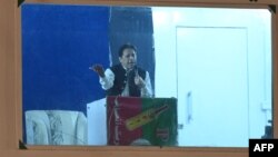 Pakistan's former prime minister Imran Khan speaks to his supporters from behind a bulletproof shield at a rally in Lahore early on March 26, 2023.