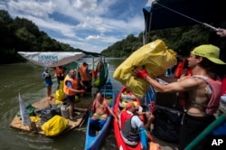 Para sukarelawan menurunkan muatan dari perahu mereka yang penuh dengan sampah plastik saat mengikuti acara Piala Plastik di dekat Tiszaroff, Hungaria, 2 Agustus 2023. (AP/Denes Erdos)