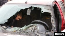 Seorang warga setempat memeriksa mobil rusak yang terkena tembakan, yang oleh pemerintah setempat disebut sebagai serangan militer Ukraina, di pemukiman Razumnoe di Wilayah Belgorod, Rusia 19 Maret 2024. (Foto: Reuetrs)