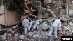 A search team look through the cracks in the rubble of a house as they look for missing persons Leyla Habip and Nejat Habip in the aftermath of the deadly earthquake, in Hatay, Turkey, Feb. 18, 2023.