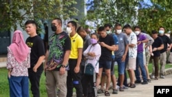 Voters wait in line to cast their ballot during advance voting at a polling station in a school in Narathiwat, southern Thailand, on May 7, 2023, a week ahead of the May 14 general election.