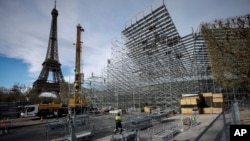 FILE - Workers build the stands for the upcoming Olympic Games on the Champ-de-Mars just beside the Eiffel Tower, in Paris, April 1, 2024 in Paris. 