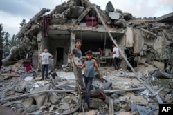 Warga Palestina menyaksikan kehancuran pasca serangan udara Israel di Deir al Balah, Jalur Gaza, 30 April 2024. (Foto: AP)