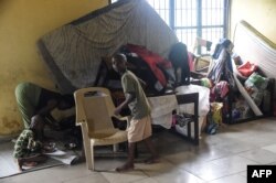 FILE - A mother and children stand beside wares and mattresses in an internally displaced people's camp, where flood evacuees are accommodated, at Community Primary School in Ihuike, Niger delta region of Ahoada, Rivers State, southern Nigeria, on Oct. 21, 2022.