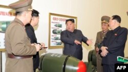 김정은(가운데) 국무위원장이 600㎜ 초대형방사포와 순항미사일 화살-1형·화살-2형, 단거리탄도미사일 화성-11형 등에 탑재 가능한 전술 핵탄두 '화산-31'을 살펴보고 있다. 관영 매체가 지난달 28일 공개한 장면. (자료사진)