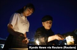 Orang-orang menyalakan dupa untuk para korban bom atom yang dijatuhkan di Hiroshima oleh AS pada 1945, di Taman Monumen Perdamaian di Hiroshima, bagian barat Jepang, Minggu, 6 Agustus 2023. (Foto: Kyodo News via Reuters)